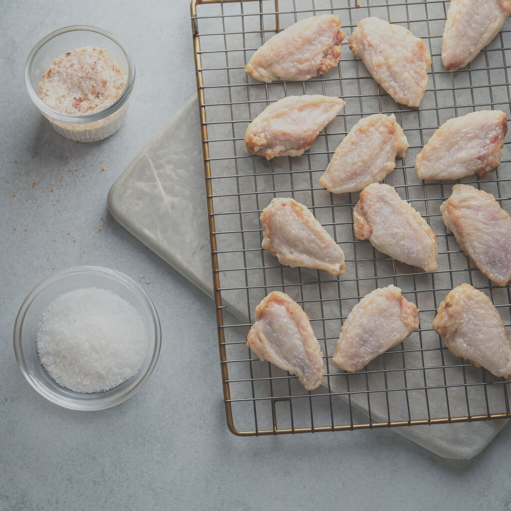 Chicken wings arranged on a cooling rack, showcasing their crispy texture and golden-brown color.