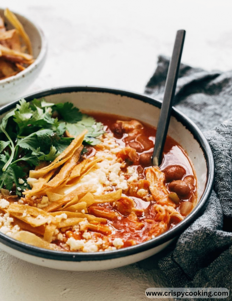 Mexican chicken soup served in a bowl, featuring vibrant vegetables and spices, garnished with fresh herbs.