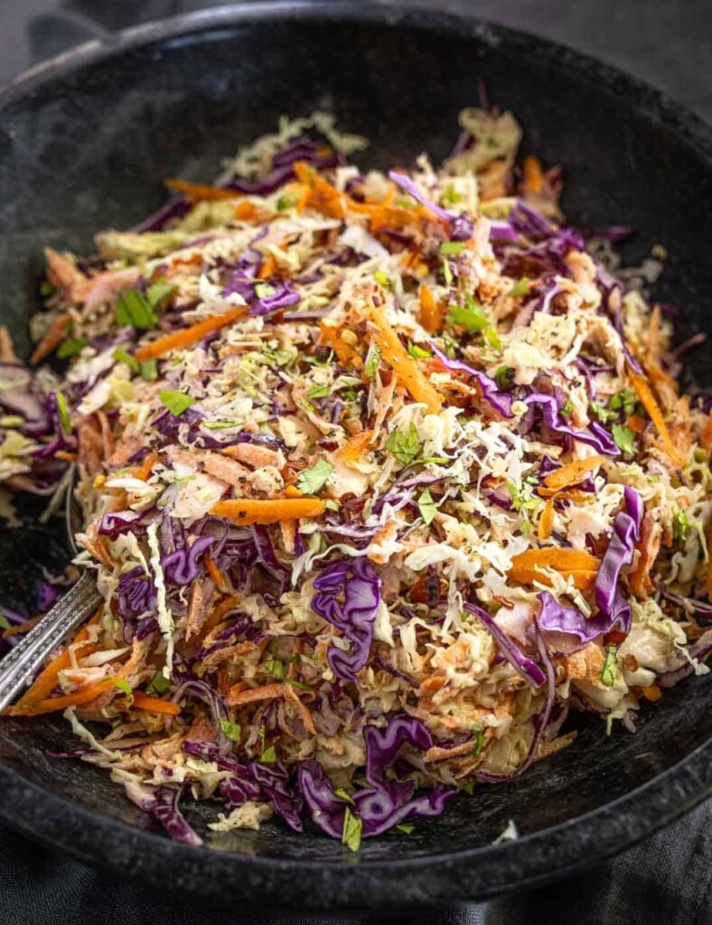 A bowl of coleslaw featuring shredded carrots and cabbage mixed together.