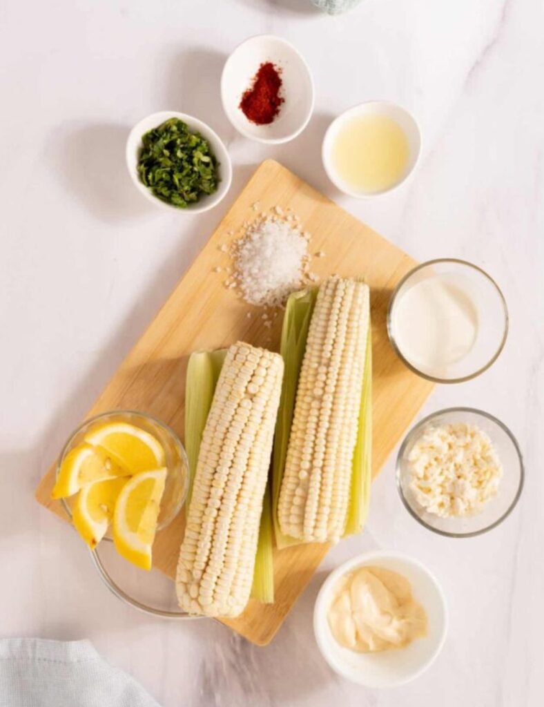 4 ears of corn, husked

1/2 cup mayonnaise

1/2 cup sour cream

1 cup crumbled Cotija cheese

1 tablespoon chili powder

1 lime, juiced

Salt to taste

Chopped cilantro for garnish