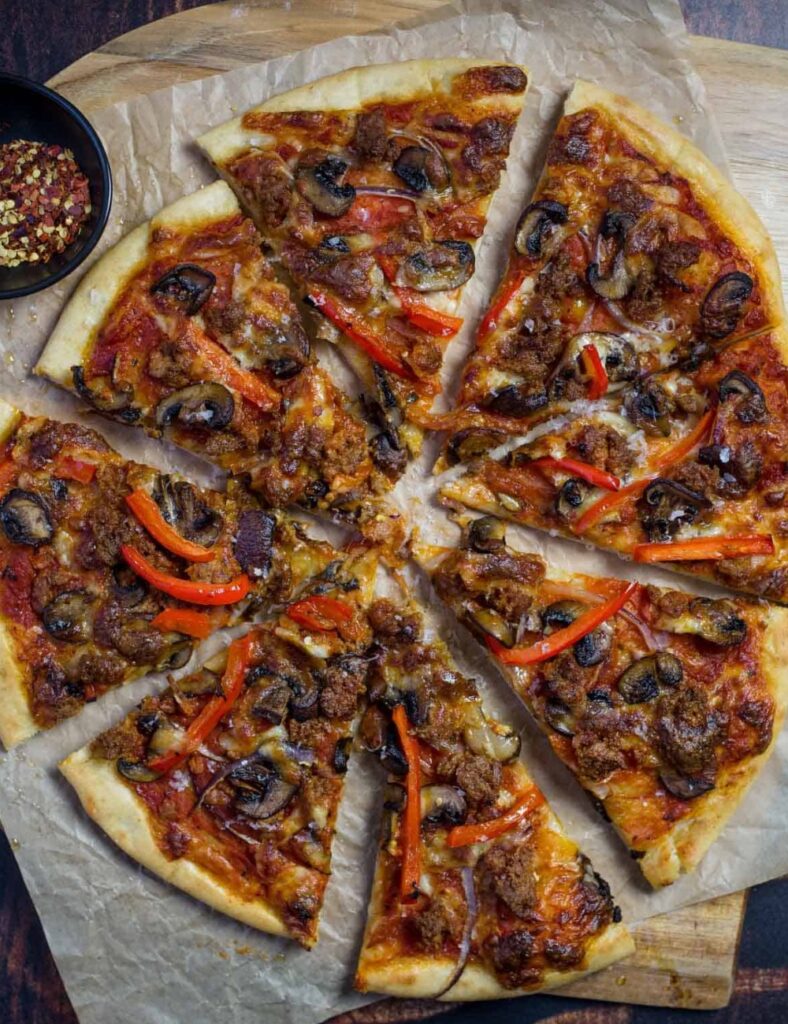 a pizza with meat and mushrooms on a table