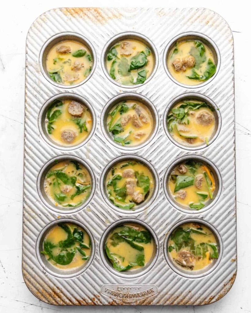 Muffin pan filled with baked egg and spinach mixture, ready for serving.