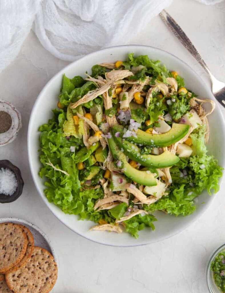 a bowl of salad with chicken and avocado