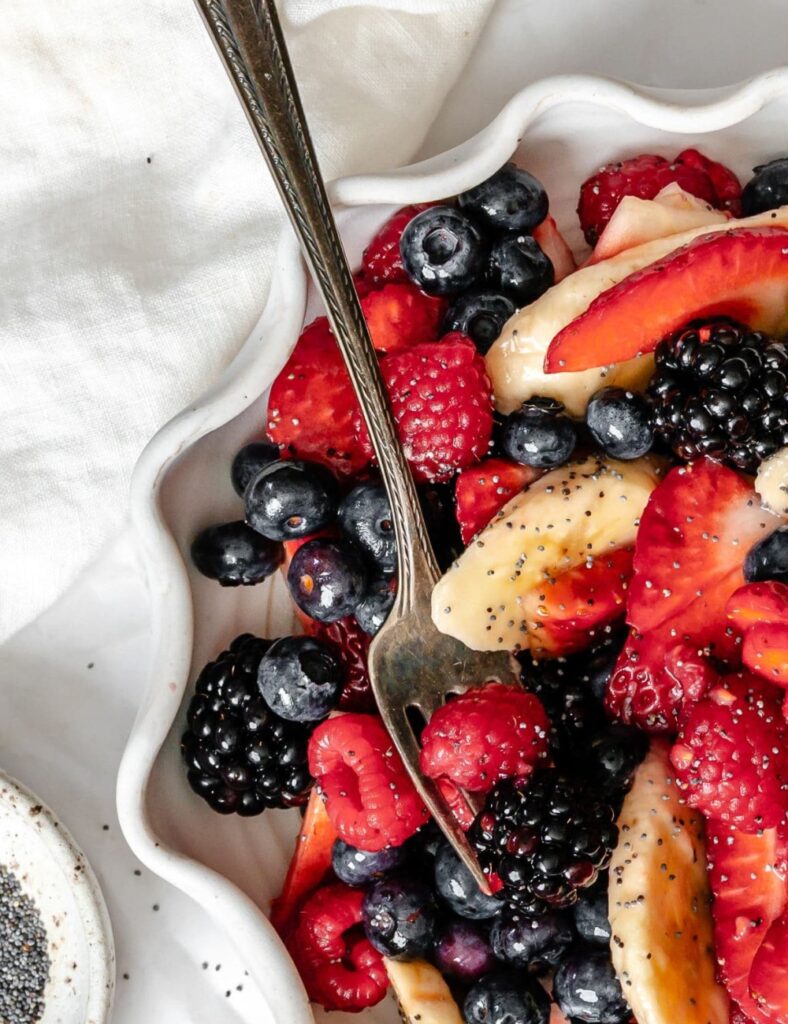 A colorful poppy seed fruit salad featuring various fresh fruits and a light dressing.