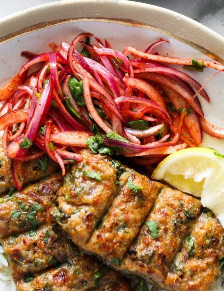 Plate of spicy Chicken Seekh Kebabs served with mint and onions