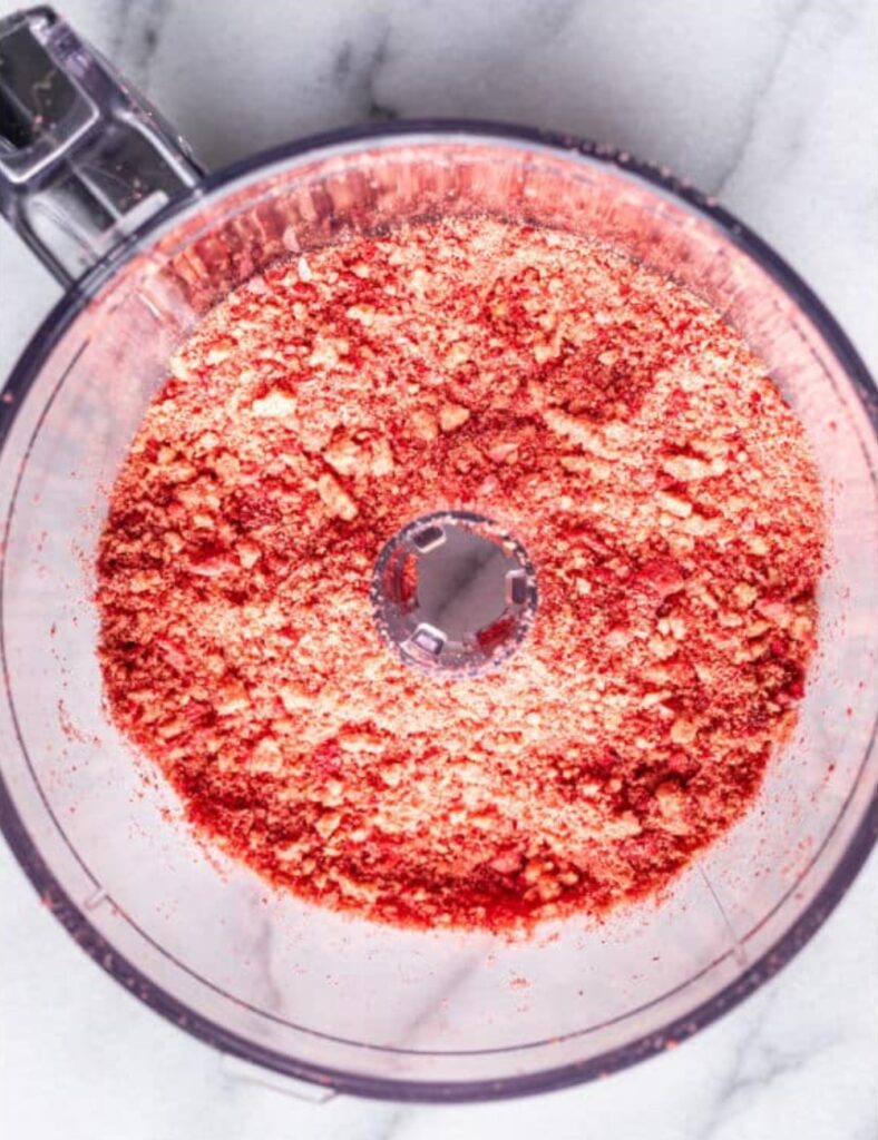 A food processor filled with vibrant red food coloring, ready for use in baking or cooking.