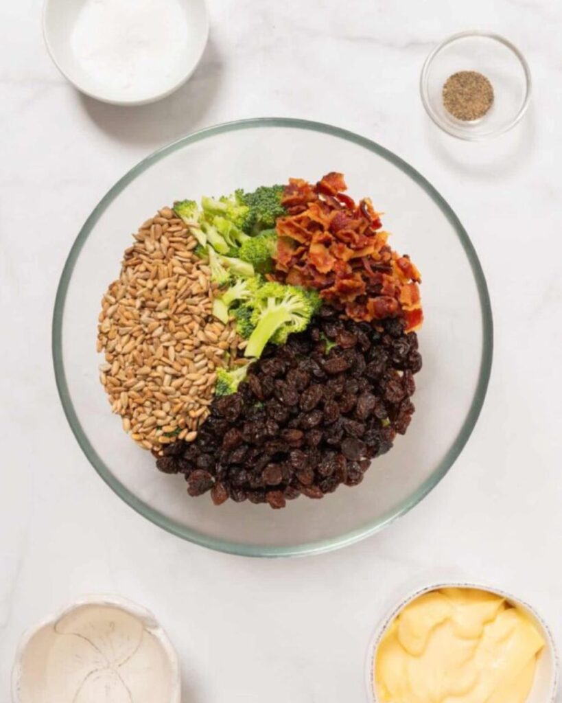 In a large bowl, combine the broccoli florets, raisins, chopped red onion, and sunflower seeds.