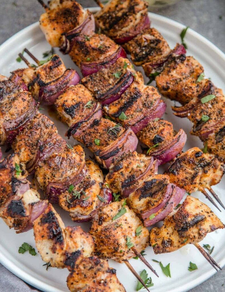 a plate of chicken skewers