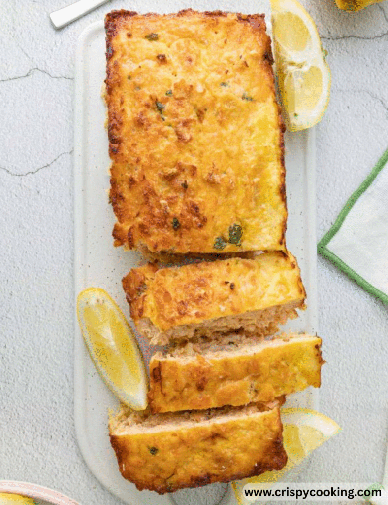 A loaf of bread accompanied by fresh lemons and slices of cheese on a wooden surface.

