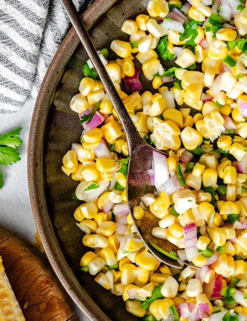 a bowl of corn salad with spoon