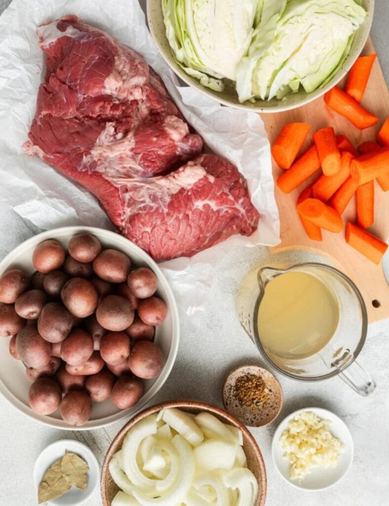 4-5 lbs corned beef brisket
1 small head of cabbage, cut into wedges
4-5 large carrots, peeled and cut into chunks
1-2 lbs small potatoes, halved
1 onion, quartered
2-3 cups beef broth
2 tablespoons yellow mustard seeds
2 tablespoons black peppercorns
Bay leaves
Salt to taste