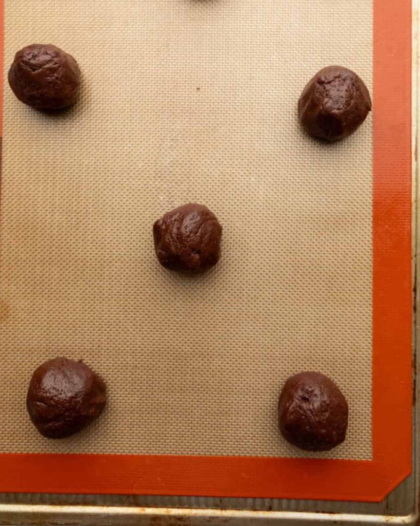 Chocolate balls arranged on a baking sheet, ready for baking or cooling.