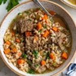 Bowl of delicious homemade beef barley soup with vegetables and herbs