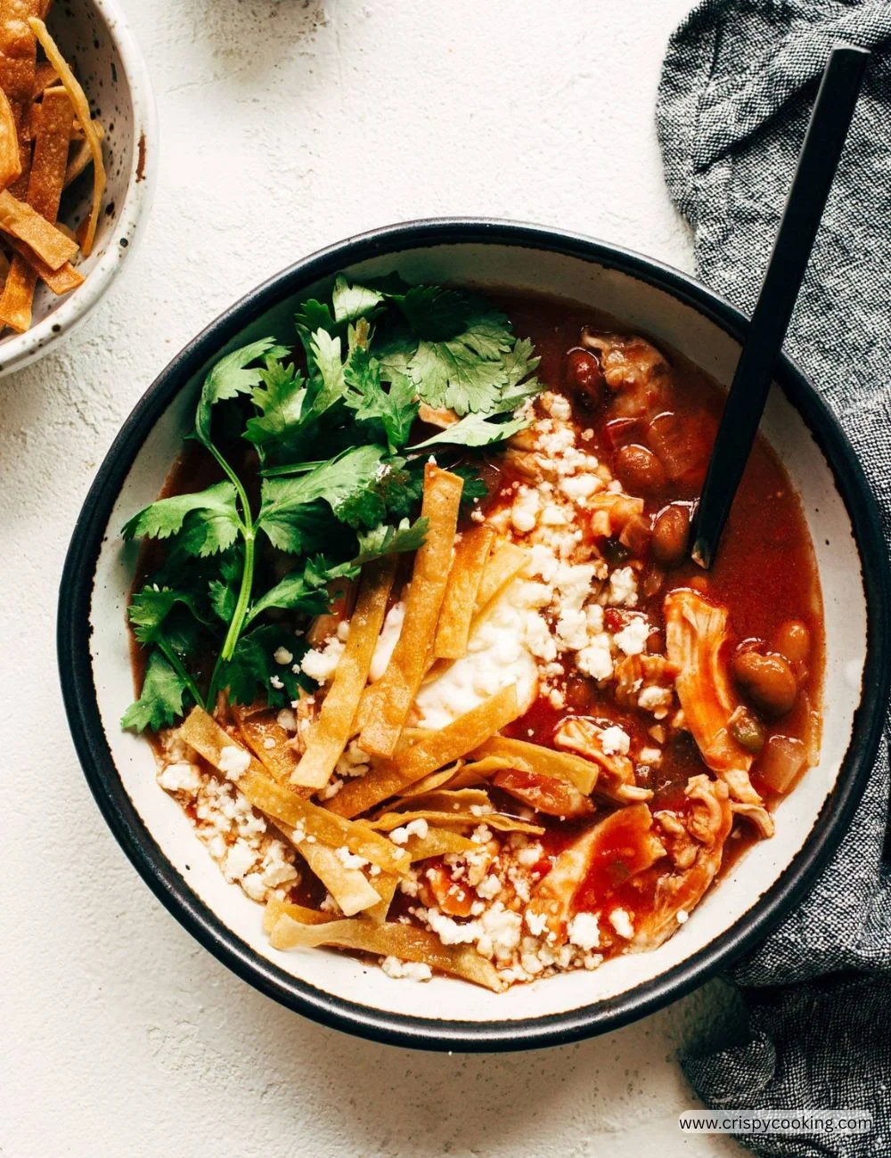 Bowl of delicious Chicken Tortilla Soup topped with tortilla strips and fresh herbs