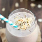 Chocolate almond coconut banana smoothie in a glass with a straw.