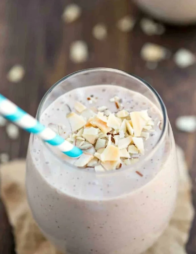 Chocolate almond coconut banana smoothie in a glass with a straw.