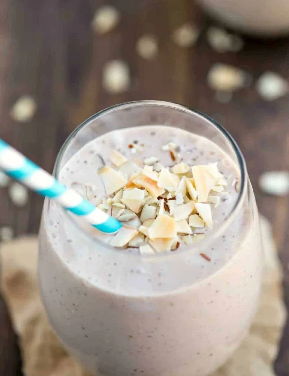 Chocolate almond coconut banana smoothie in a glass with a straw.