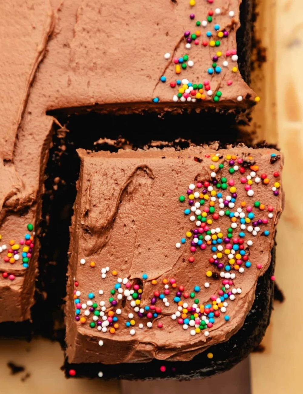 Delicious chocolate sheet cake topped with frosting on a rustic wooden table.