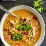 Bowl of creamy chicken taco soup garnished with cilantro and lime wedges