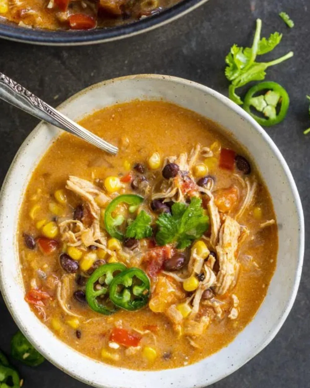 Bowl of creamy chicken taco soup garnished with cilantro and lime wedges