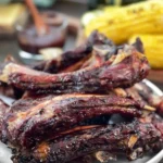 Juicy grilled beef ribs served with barbecue sauce and side dishes