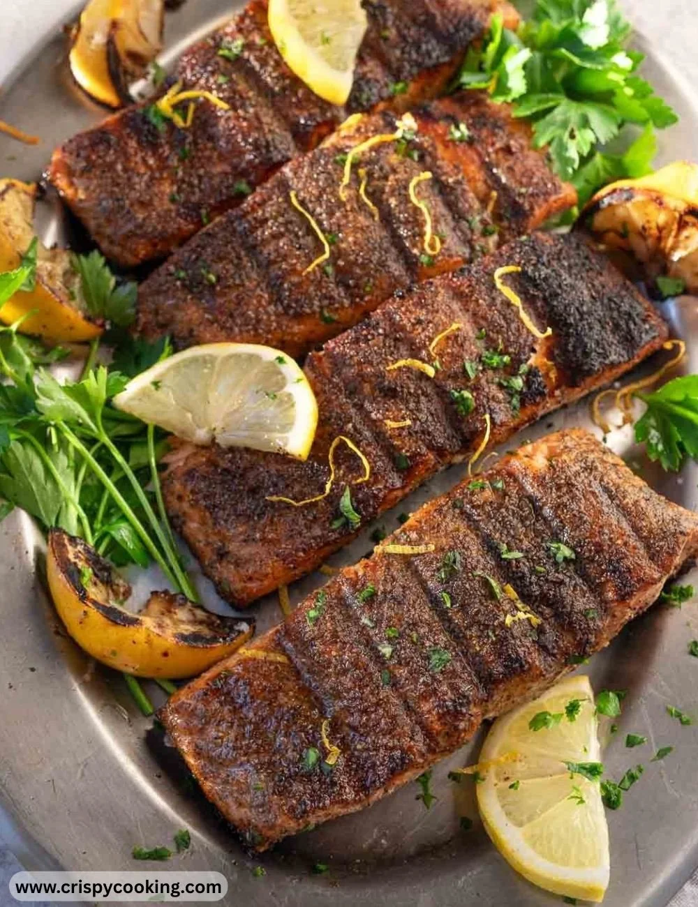 Grilled lemon pepper salmon garnished with herbs on a white plate