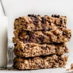 Healthy homemade peanut butter granola bars stacked on a wooden table.