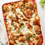 Delicious Meatball Casserole topped with melted cheese and herbs