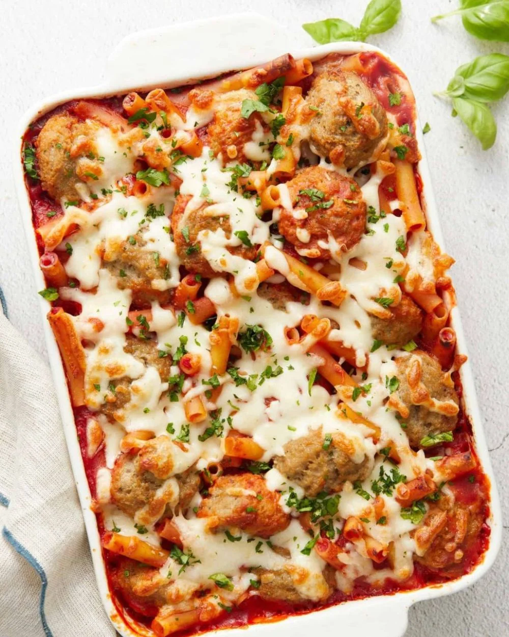 Delicious Meatball Casserole topped with melted cheese and herbs