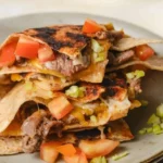 Deliciously stacked mulitas with savory meat, cheese, and salsa on a warm tortilla.