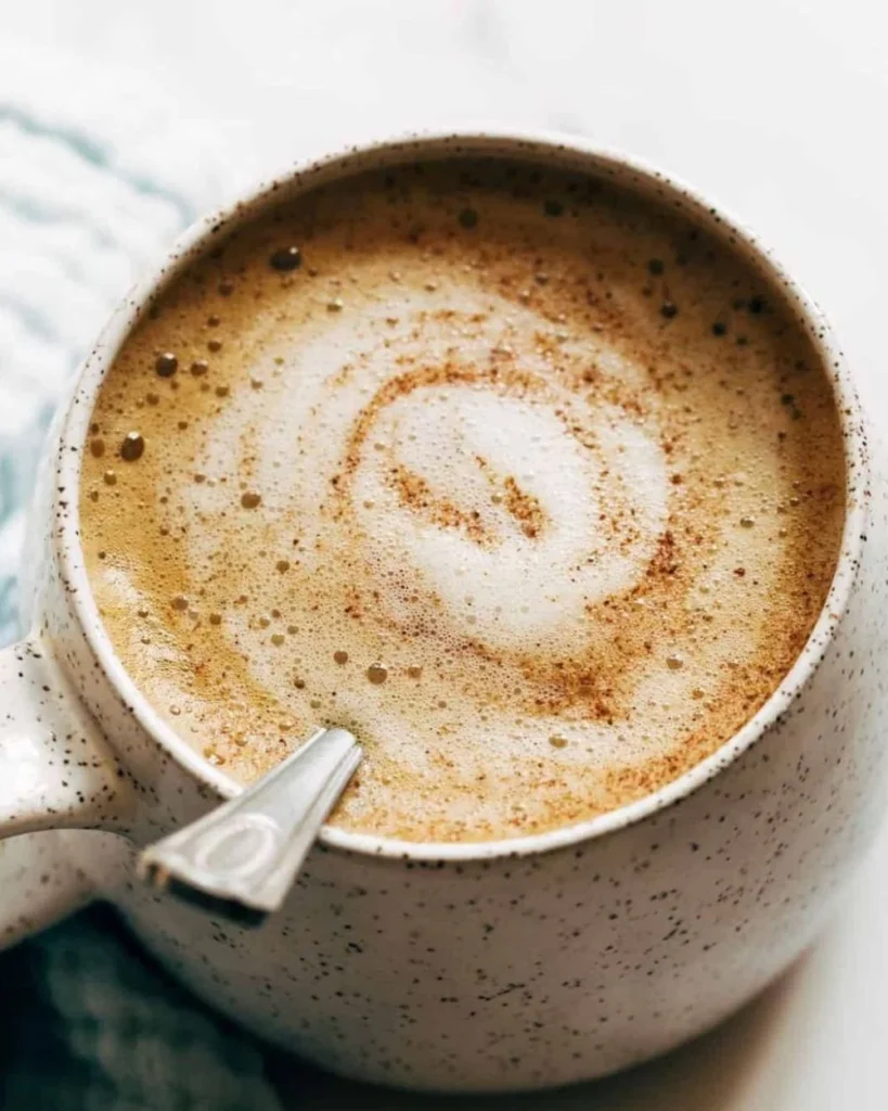 Delicious oatmilk honey latte with foam and honey drizzle in a coffee cup