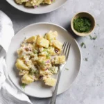 Delicious and creamy potato salad served in a bowl, garnished with herbs.