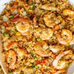 A bowl of shrimp fried rice with colorful veggies and shrimp, garnished with green onions