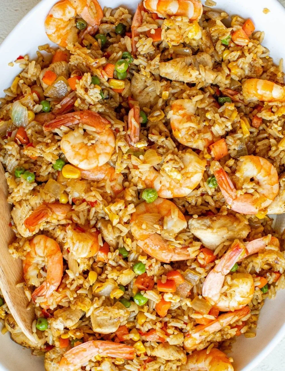 A bowl of shrimp fried rice with colorful veggies and shrimp, garnished with green onions