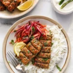 Plate of spicy Chicken Seekh Kebabs served with mint chutney and onions