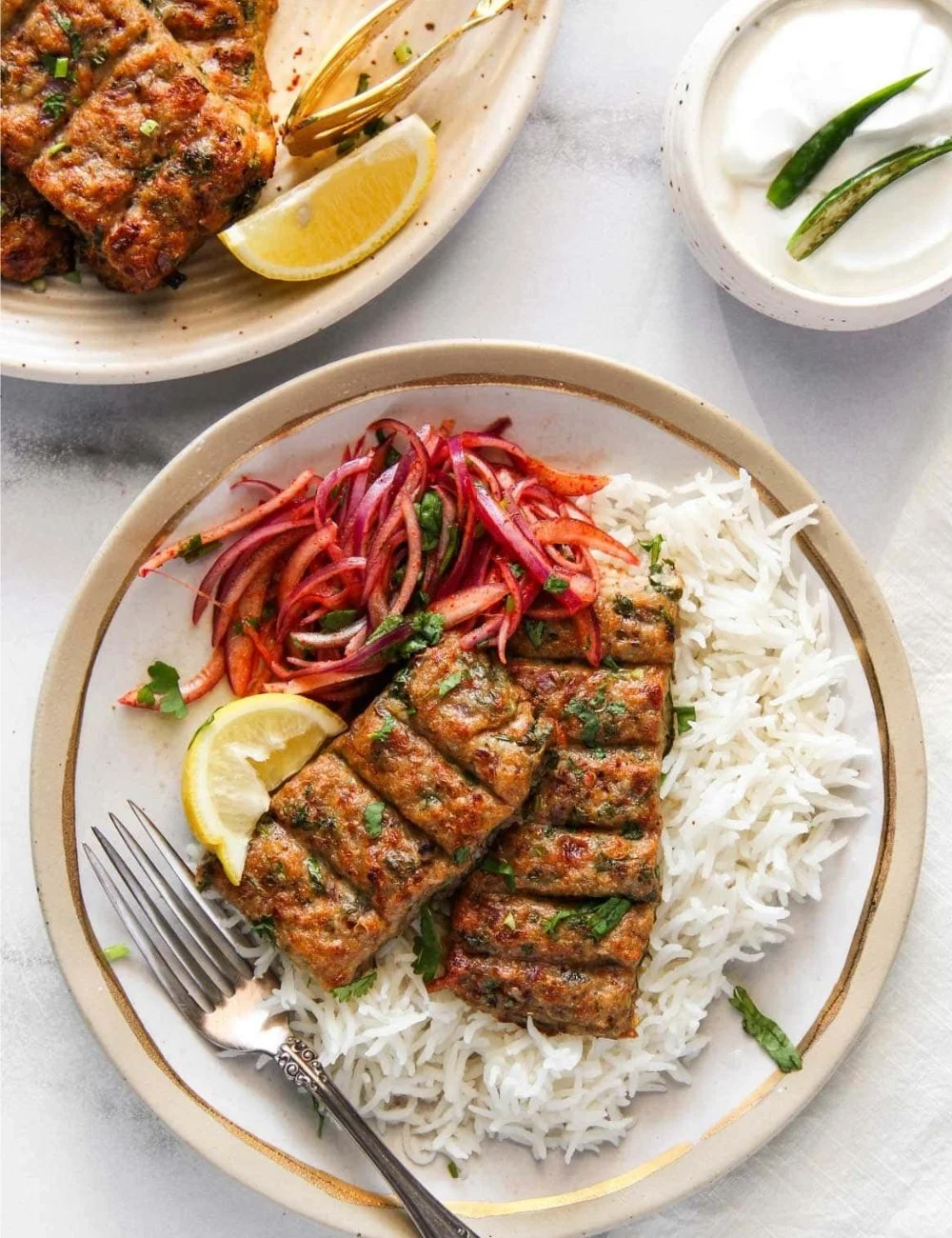 Plate of spicy Chicken Seekh Kebabs served with mint chutney and onions