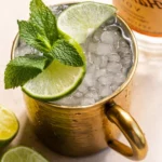 A refreshing Moscow Mule cocktail served in a copper mug with lime and mint garnish.