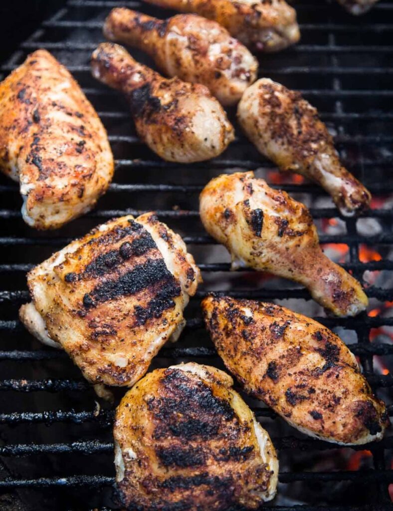 Grilled chicken served with lemon wedges on a sleek black plate, highlighting a delicious meal presentation.