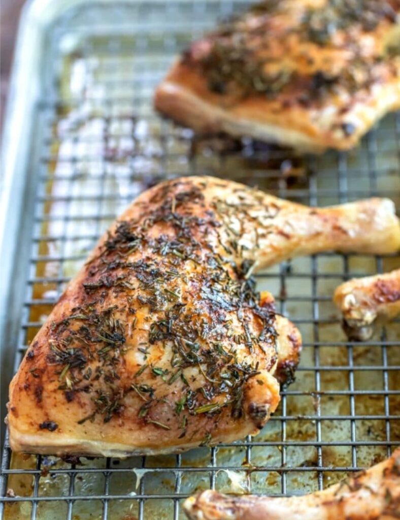 Baked chicken thighs garnished with fresh rosemary, showcasing a golden-brown, crispy skin and juicy meat.
