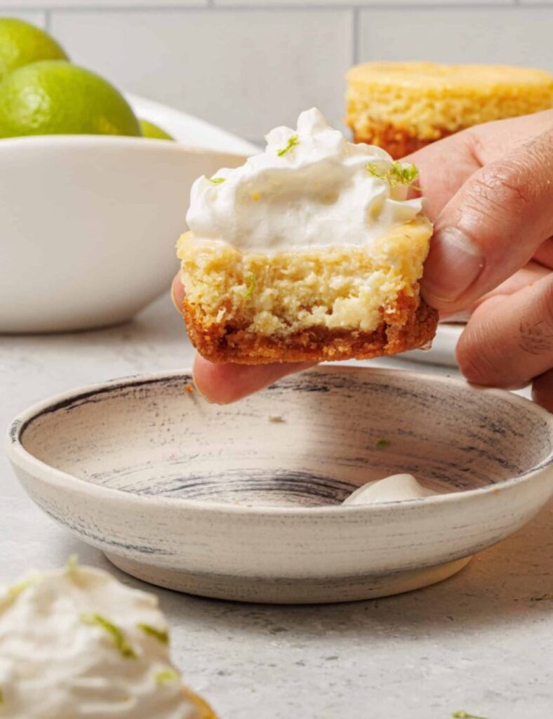A small key lime pie featuring whipped cream and decorative lime slices on top.