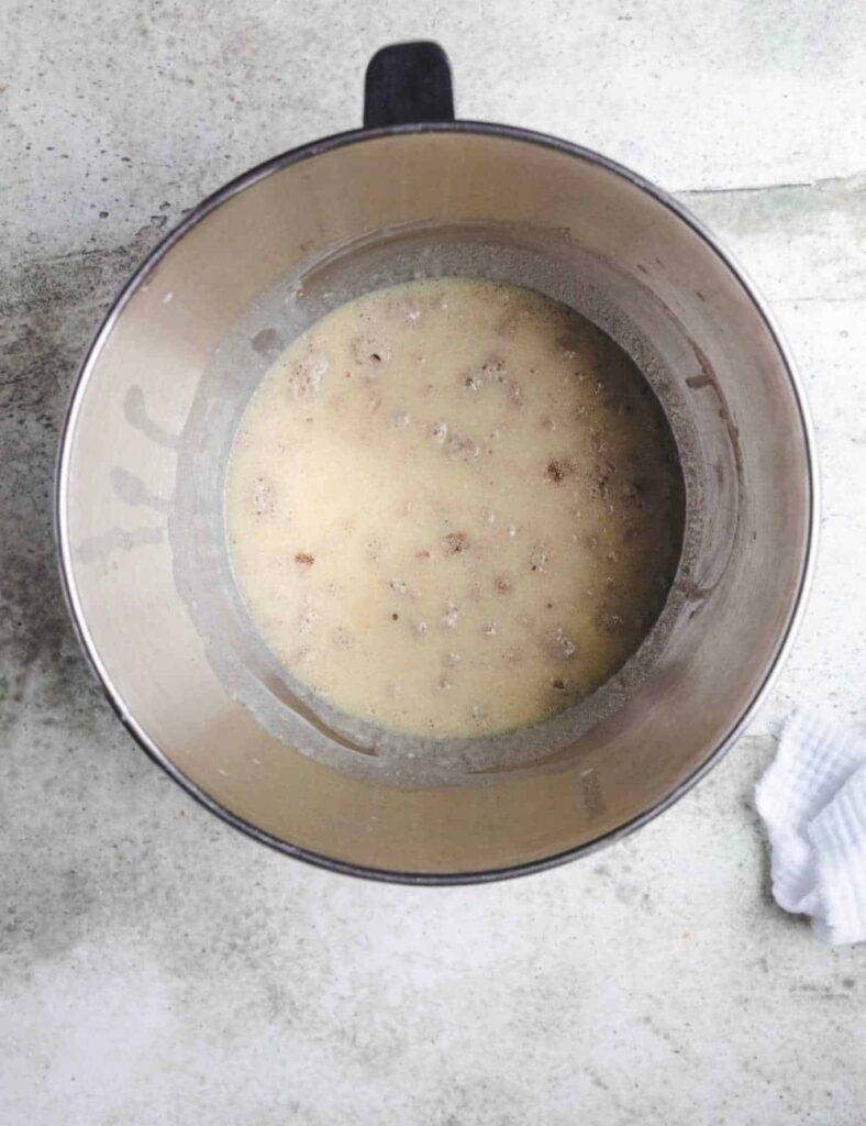 3. A metal bowl with liquid and a white towel are positioned together on a countertop.

