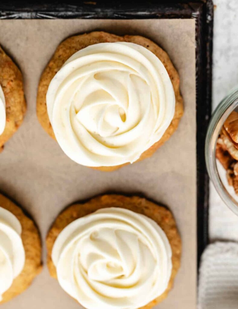 Freshly baked carrot cake cookies with cream cheese frosting and grated carrots