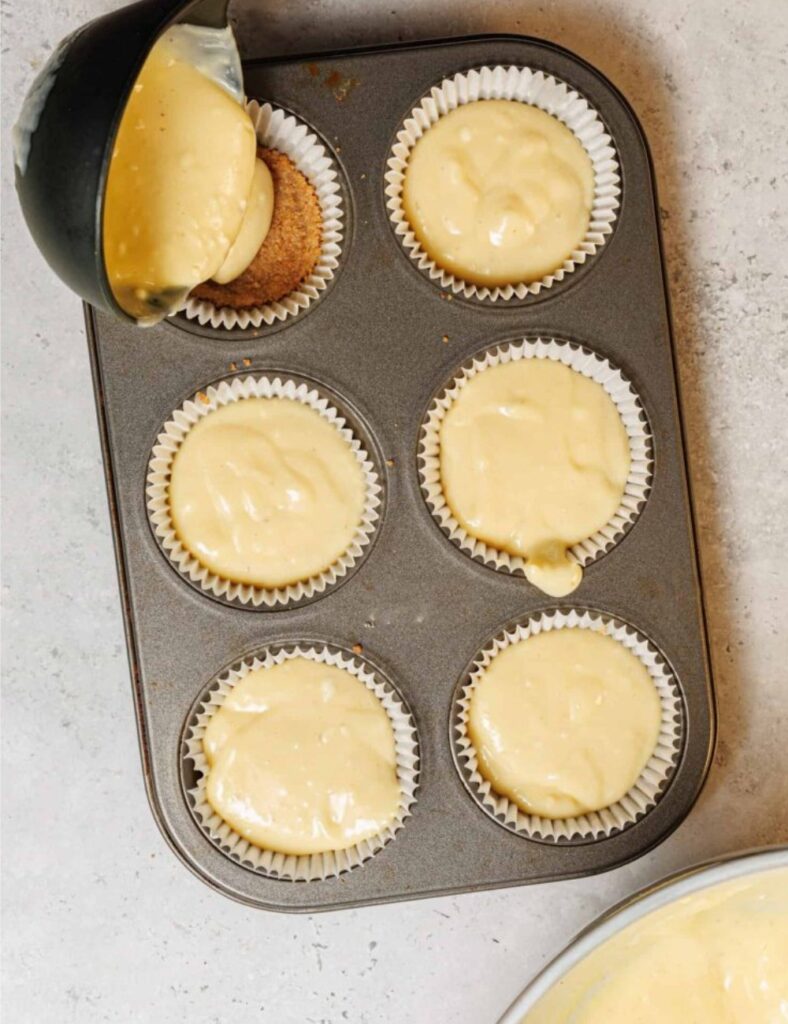 A muffin pan featuring a spoon placed in the middle, indicating preparation for baking.
