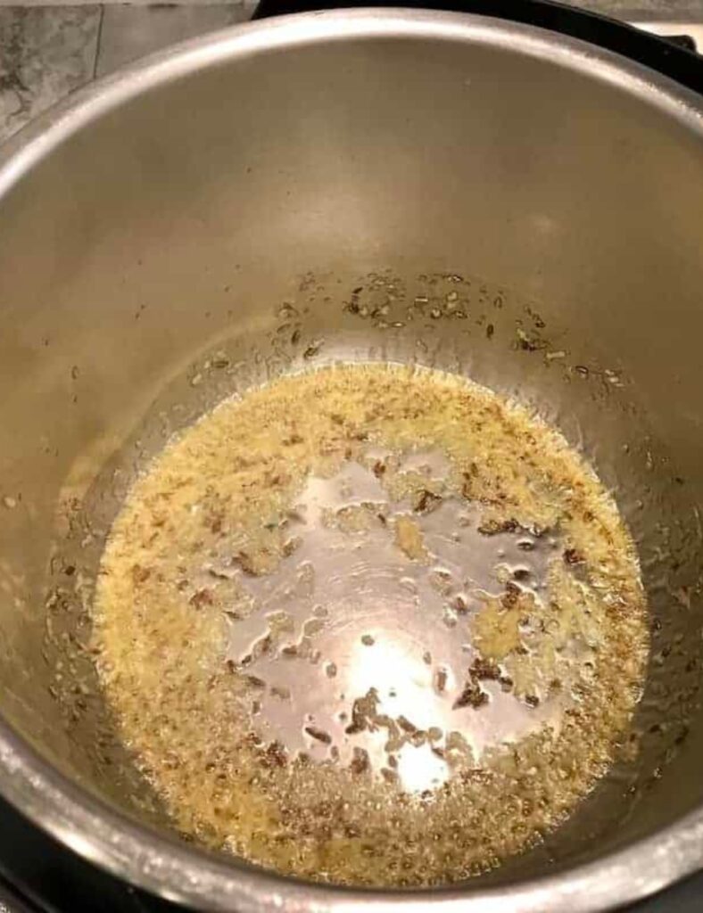 A stove-top pan containing oil and assorted ingredients, prepared for a cooking process.