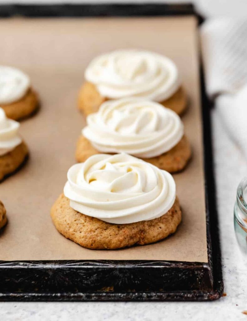 Freshly baked carrot cake cookies with cream cheese frosting and grated carrots