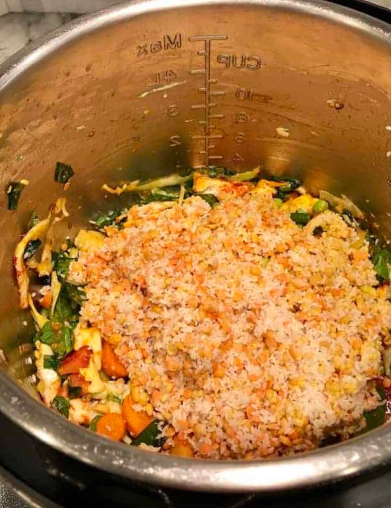 A pan with oil and other ingredients heating on a stove, indicating meal preparation.