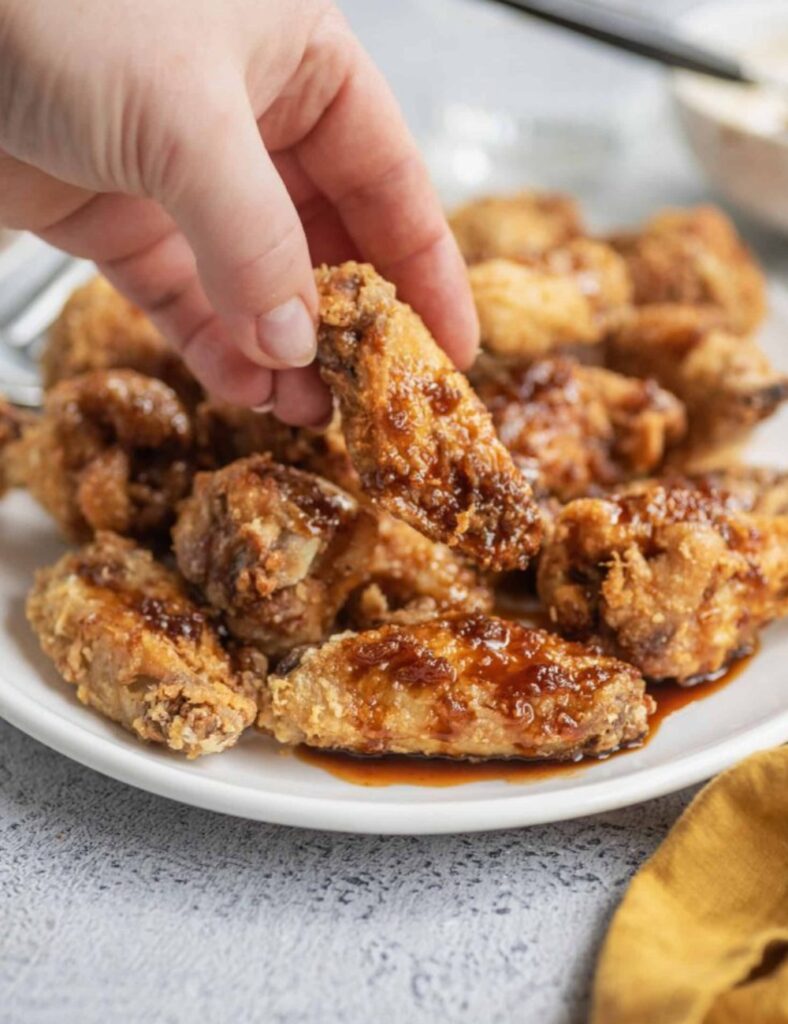 A plate of golden-brown chicken wings garnished with parsley, ready to be served.