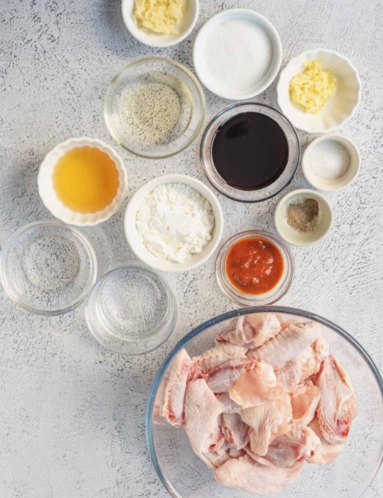 2 lbs chicken wings, 
1 cup all-purpose flour, 
1 cup cornstarch, 
1 teaspoon baking powder, 
1 teaspoon salt, 
1 teaspoon black pepper, 
2 cups vegetable oil (for frying), 
1/2 cup gochujang (Korean chili paste), 
1/4 cup soy sauce, 
1/4 cup honey,
2 tablespoons rice vinegar, 
2 cloves garlic (minced), 
1 tablespoon sesame oil, 
Sesame seeds (for garnish), 
Green onions (for garnish)