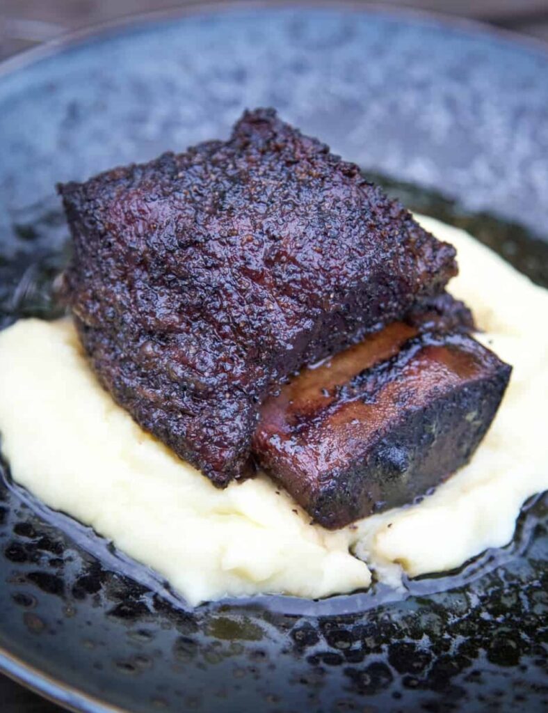 Deliciously smoked beef short ribs on a grill, ready for serving.