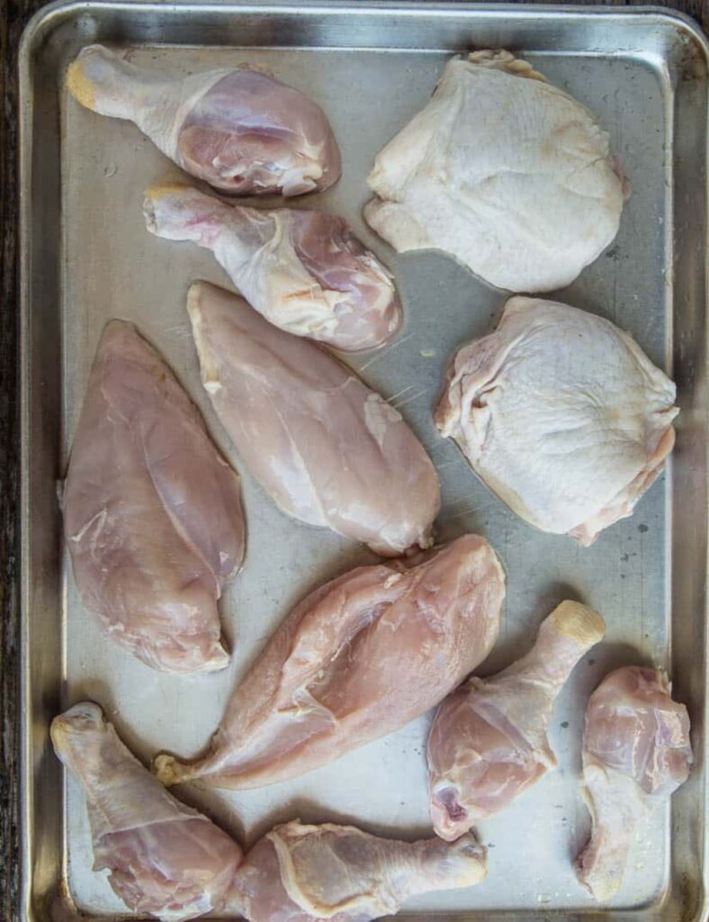 Raw chicken legs arranged on a baking sheet, ready for seasoning and cooking.